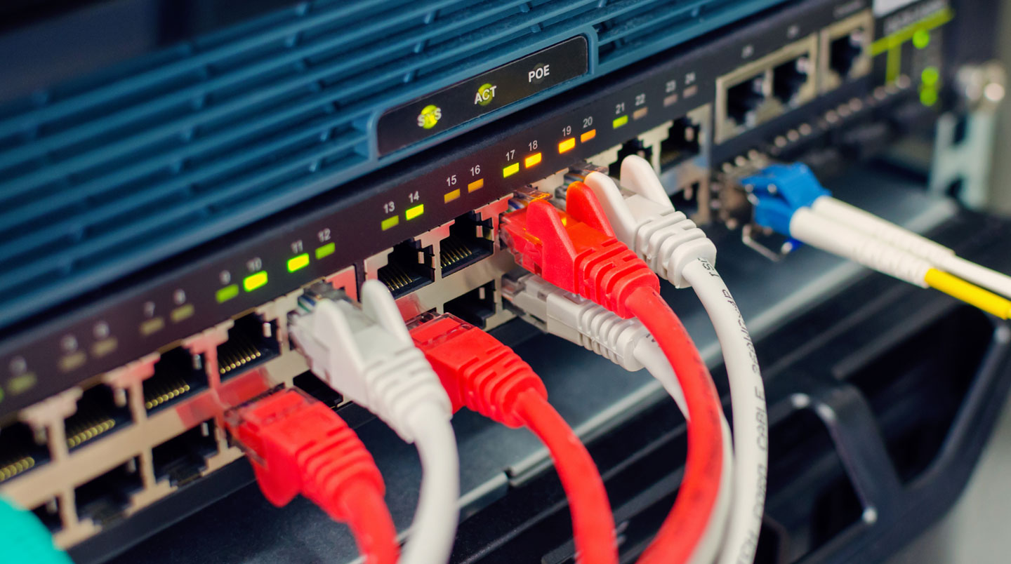 Gros plan extrême sur un connecteur RJ45 Ethernet branché dans un switch réseau, avec mise au point nette sur le connecteur et arrière-plan flouté